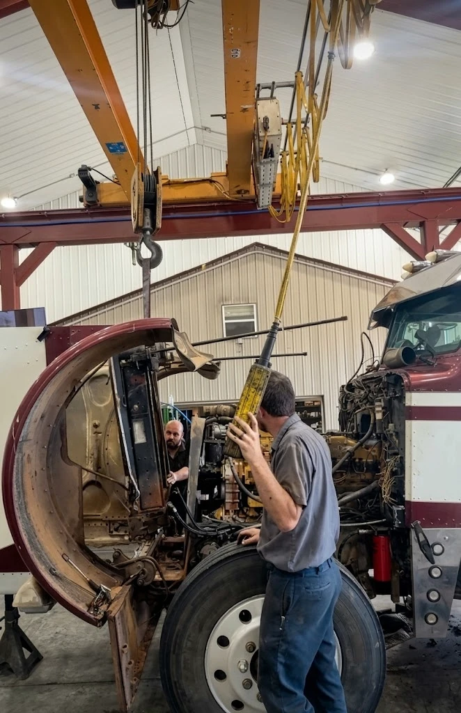 Mechanic installing a new charge air cooler on a semi truck — OEM-spec replacement CAC being fitted into the engine bay