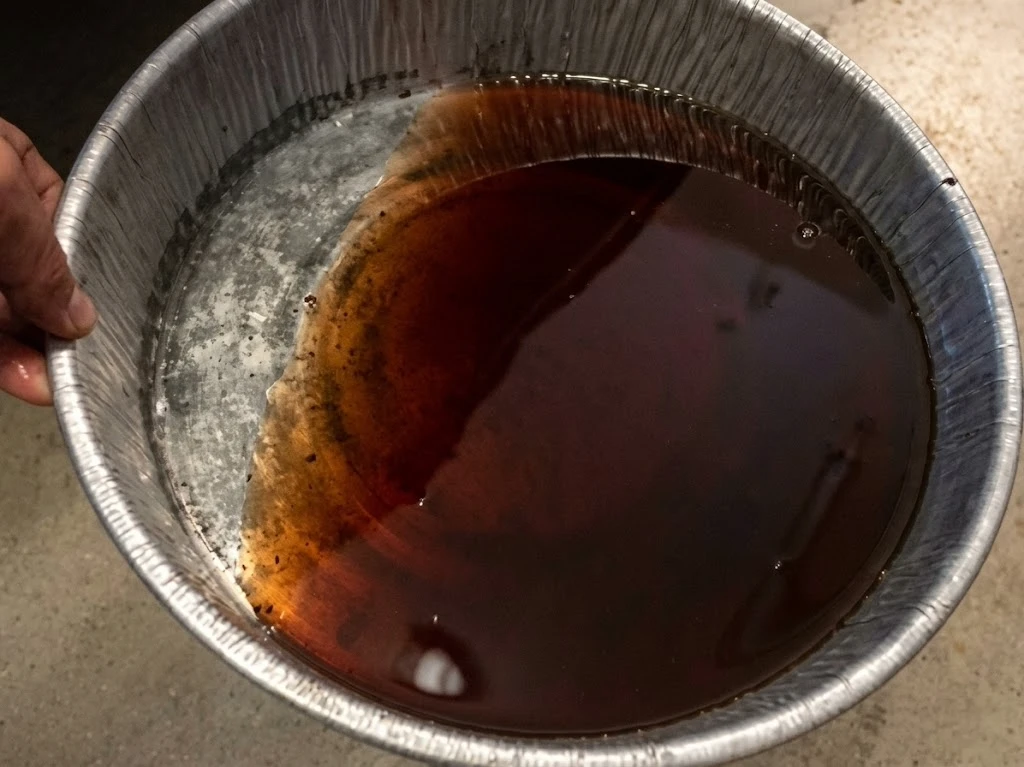 Dark rusty brown old coolant in drain pan from semi truck — degraded inhibitors and internal corrosion
